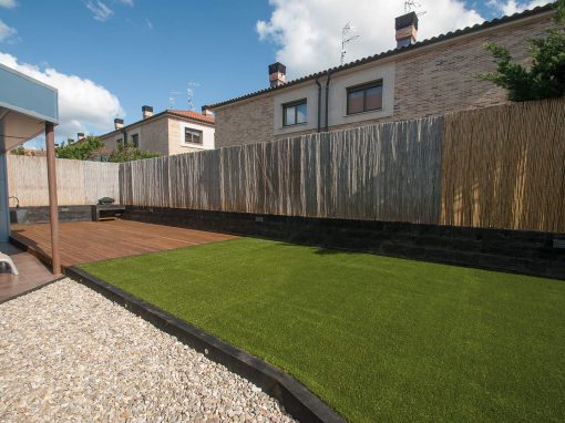 Extenso jardín con césped artificial, tarima, áridos…
